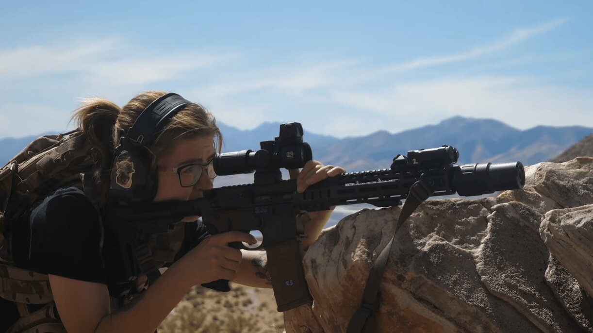 Shooter aiming suppressed 5.56 AR-15 rifle